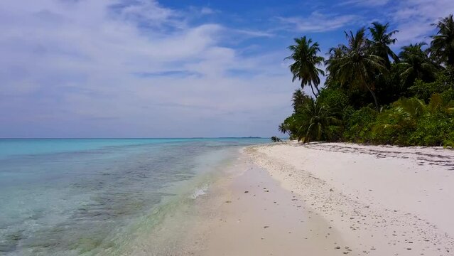 Maldives islans. Drone view of beautiful seamless never ending footage while turquiose sea waves breaking on sandy coastline. Aerial shot of golden beach meeting deep blue ocean water and foamy waves