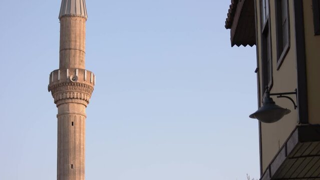 Beautiful street with historical buildings in Turkey. Minaret on blue sky background.