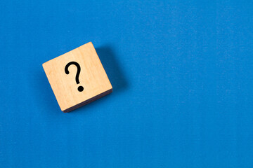 Cubo de madera con un signo de interrogación sobre un fondo azul liso y aislado. Vista superior y...
