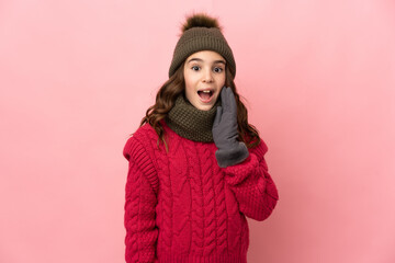 Little girl with winter hat isolated on pink background with surprise and shocked facial expression
