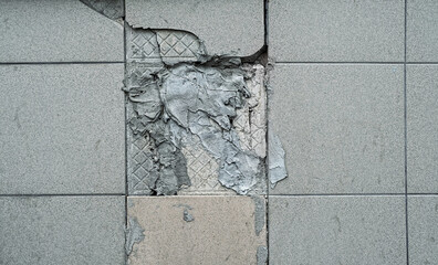 Broken tiles and concrete texture of dirty grey wall close up. Cracked old wall panels  close up. 