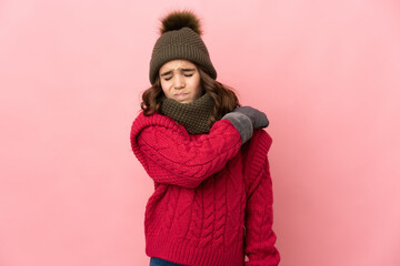 Little girl with winter hat isolated on pink background suffering from pain in shoulder for having...