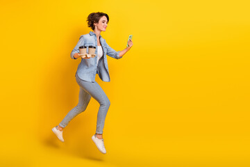 Fototapeta na wymiar Full body profile side photo of young girl jump hold mobile run cappuccino break isolated over yellow color background