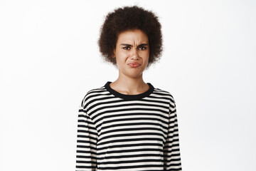 Image of african girl express disgust or dislike, grimacing from aversion, refusing, rejecting smth bad, standing over white background