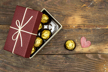 gift or present box of golden premium chocolate sweets and small wooden heart, happy valentine's concept