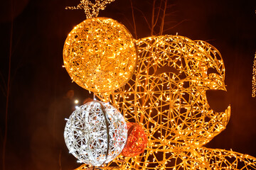 Illuminated sculpture of golden bear at city Christmas celebration.