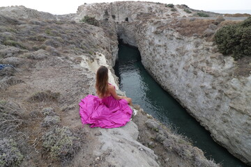 Fototapeta premium woman in a pink dress on a beach in milos greece