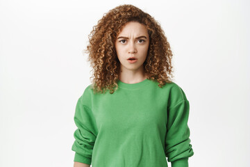 Portrait of shocked and disgusted young woman, showing tongue and grimacing from dislike, looking...