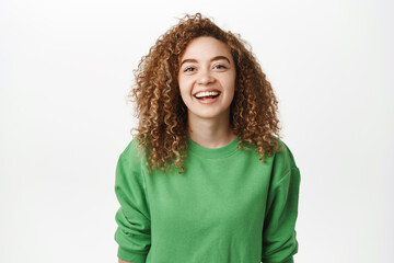 Image of amazed curly woman laughing and smiling with excitement, looking with astonished face,...