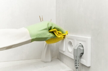washing tiles on the wall. close-up of a female hand in a rubber glove and washing tiles on the wall with a yellow rag