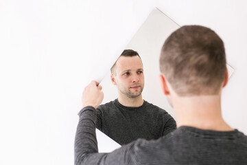 Young man standing with a mirror in his hands