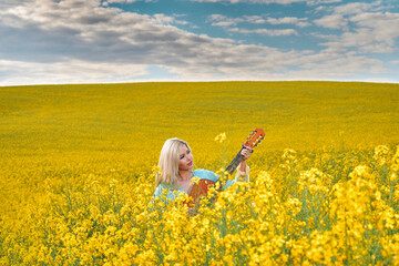 sexy woman in the field with a guitar. concept freedom, inspiration, relaxation