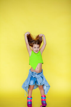 Funny little blonde girls 6 years old in everyday bright clothes posing isolated on a yellow studio background. The concept of a child's lifestyle. Layout of the copy space. The rollers are dressed.Ba