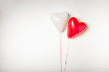 Two heart shaped balloons on a white background with space for text