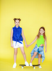 Funny little blonde girls 6-10 years old in everyday bright clothes pose isolated on the yellow...