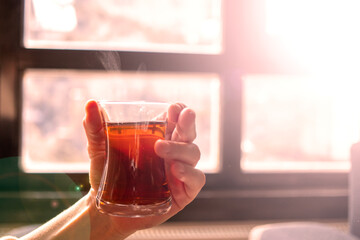 Black tea in a thin-bellied glass, Turkish tea. tea on the smoke. in woman's hand.