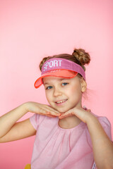 A funny little blonde girl of 10 years old in everyday bright clothes poses alone on a pink studio background. The concept of a child's lifestyle. The location of the copy space. Background for your t