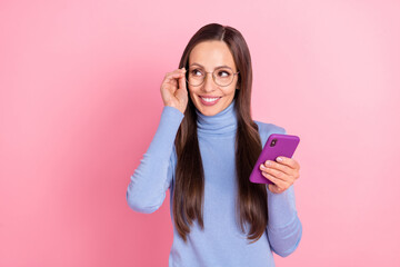 Photo of minded thoughtful lady hold telephone look empty space wear specs blue turtleneck isolated pink color background