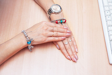 beautiful women's hands with jewelry and manicure on the table near the keyboard