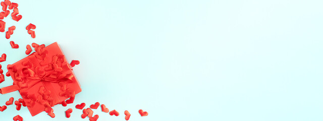 Blurred Valentine's Day composition with sRed present gift box on Blue banner background with red hearts. The concept of gifts relationships holidays. Valentine's Day background. Flat lay, top view.