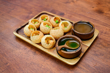 Panipuri In dian Food and wooden plate on Wooden Table - obrazy, fototapety, plakaty