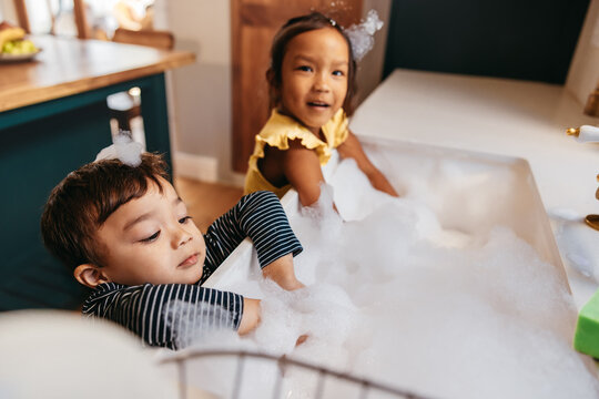 Boy and girl playing with soap foam at home