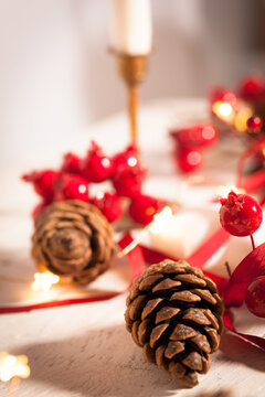 Christmas table decoration with pine cone, twig of howthorn and candle.