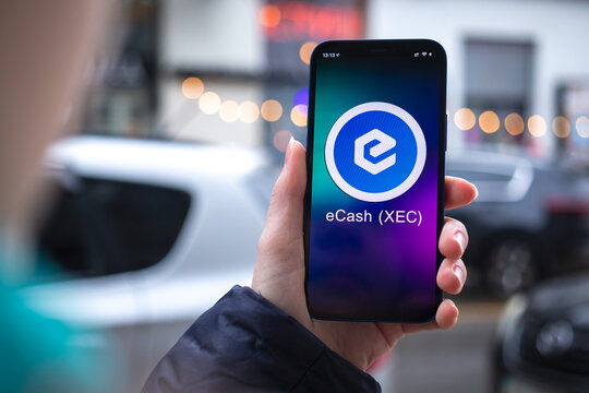 eCash XEC coin symbol. Trade with cryptocurrency, digital and virtual money, mobile banking. Hand with smartphone, screen with crypto icon close-up photo