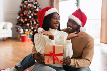 Portrait of happy black family celebrating Christmas giving present