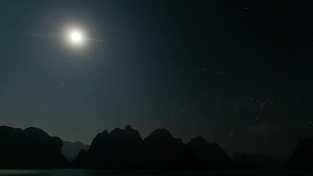 time lapse moon shine over the mountain range in the lake.. Quiet nights on the lake without distractions.. The moon shine above the mountain peaks, casting reflections into the lake.