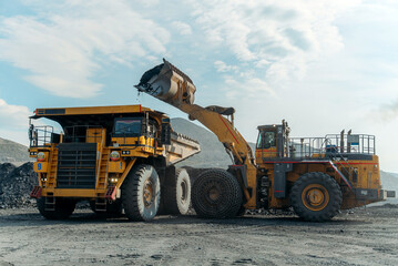 Obraz premium A loader loads ore into a dump truck.