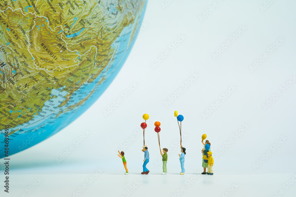 Poster A family with many children is standing in a row in front of a huge globe with colorful balloons.