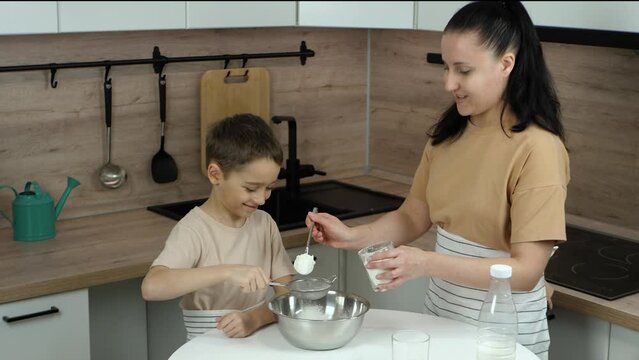 Happy family: Mom and baby spend time together. Mom and son are making dough in the kitchen. Mom and baby are playing with flour. mother s day. what's cooking