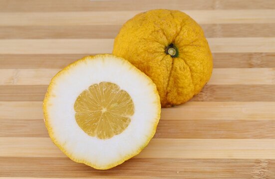Halves of a citron fruit on a two tone cutting board. Its scientific name is Citrus medica