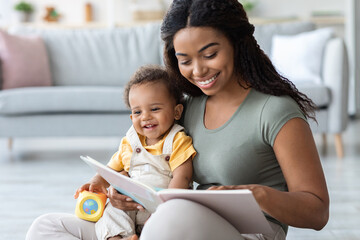 Baby Development. Young Black Mommy Reading Book With Infant Son At Home - obrazy, fototapety, plakaty