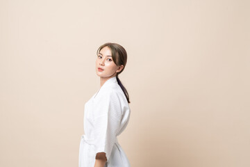 Portrait Beautiful young Asian women in bathrobe or spa suit on brown isolated studio background.