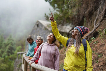 Multiracial women enjoy trekking day in the mountain forest with stone house in the background