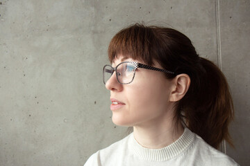 Portrait of a young red-haired woman in glasses. Thoughtful, dreamy face