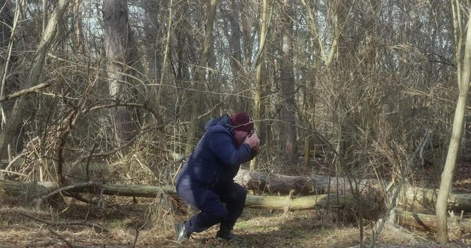 a photographer squatting takes pictures on an old film camera in the forest