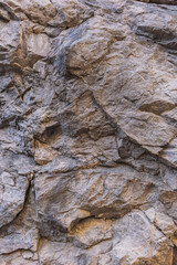 Vertical color photography of real stony textured surface of mountain. Abstract flatlay texture of stones