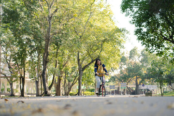 Fototapeta premium asian woman biking bicycle with her cat in backpack at park