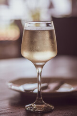 A glass of white wine on a table in a restaurant. Vintage toned, retro style.