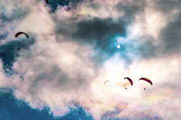 Obraz na płótnie Canvas Paragliding adventure sport against bright sun on cloudy sky