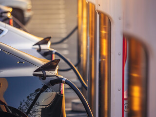 Electric cars charging at charging station outdoors at sunset. - 484699085
