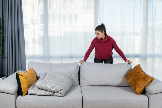 Young Woman Making Bed After Afternoon Sleeping. Female Make Her Sofa And Blanket On The Place Because She Like To Rest And To Take A Nap After Lunch Or When She Come Home From Work.