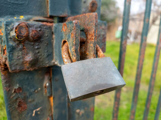 Rusty old padlock locked on gate of metal grid fence. Entrance forbidden, security safety,