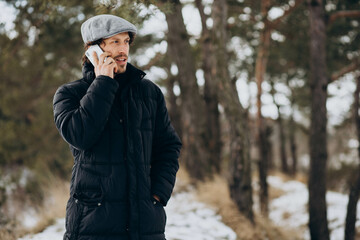 Handsome man talking on the phone in a winter park