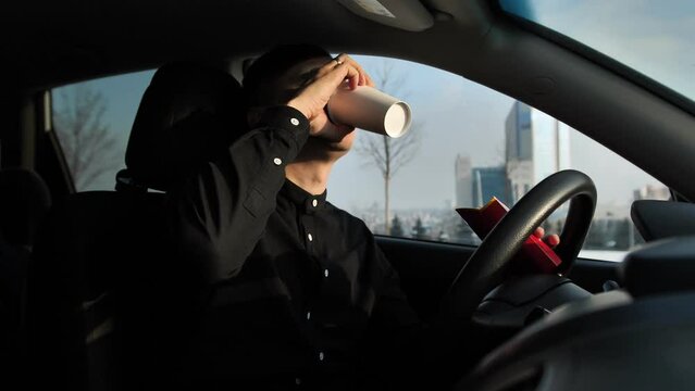 Fast food, junk food in the hand of a young businessman in a suit. A businessman is having breakfast in the car. The driver is having lunch