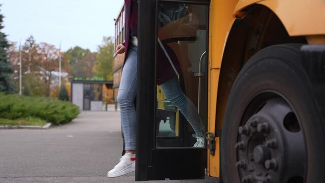 Close-up of cheerful multiracial high school students getting off yellow school bus hurrying to studies. Positive secondary school pupils jumping off steps of school bus rushing to their lessons