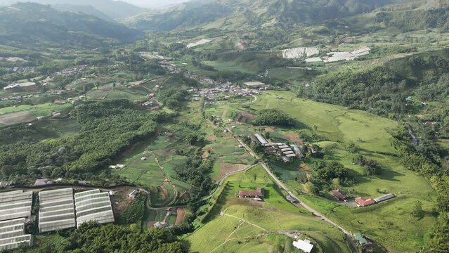 Vista de pueblo en un valle rodeado por monta&ntilde;as y campos de cultivo.